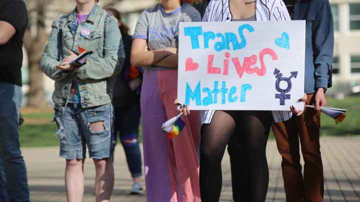 protestors with sign that says trans lives matter