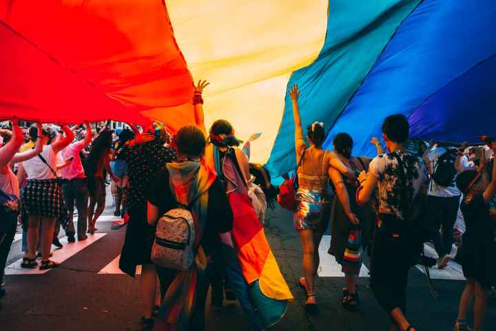 People marching under a rainbow parachute