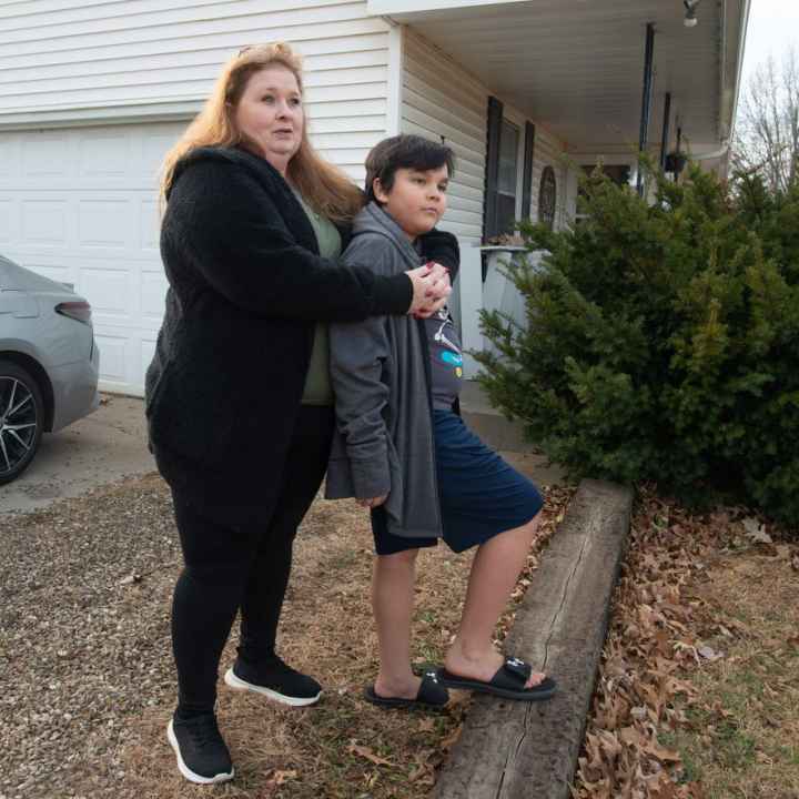 Brandy Carlson stands in yard with son, Michael