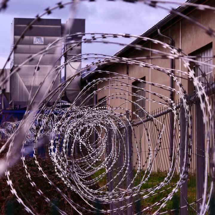 Barbed wire fence with prison in background