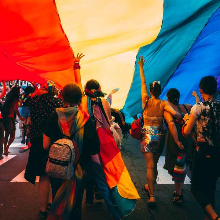 People marching under a rainbow parachute